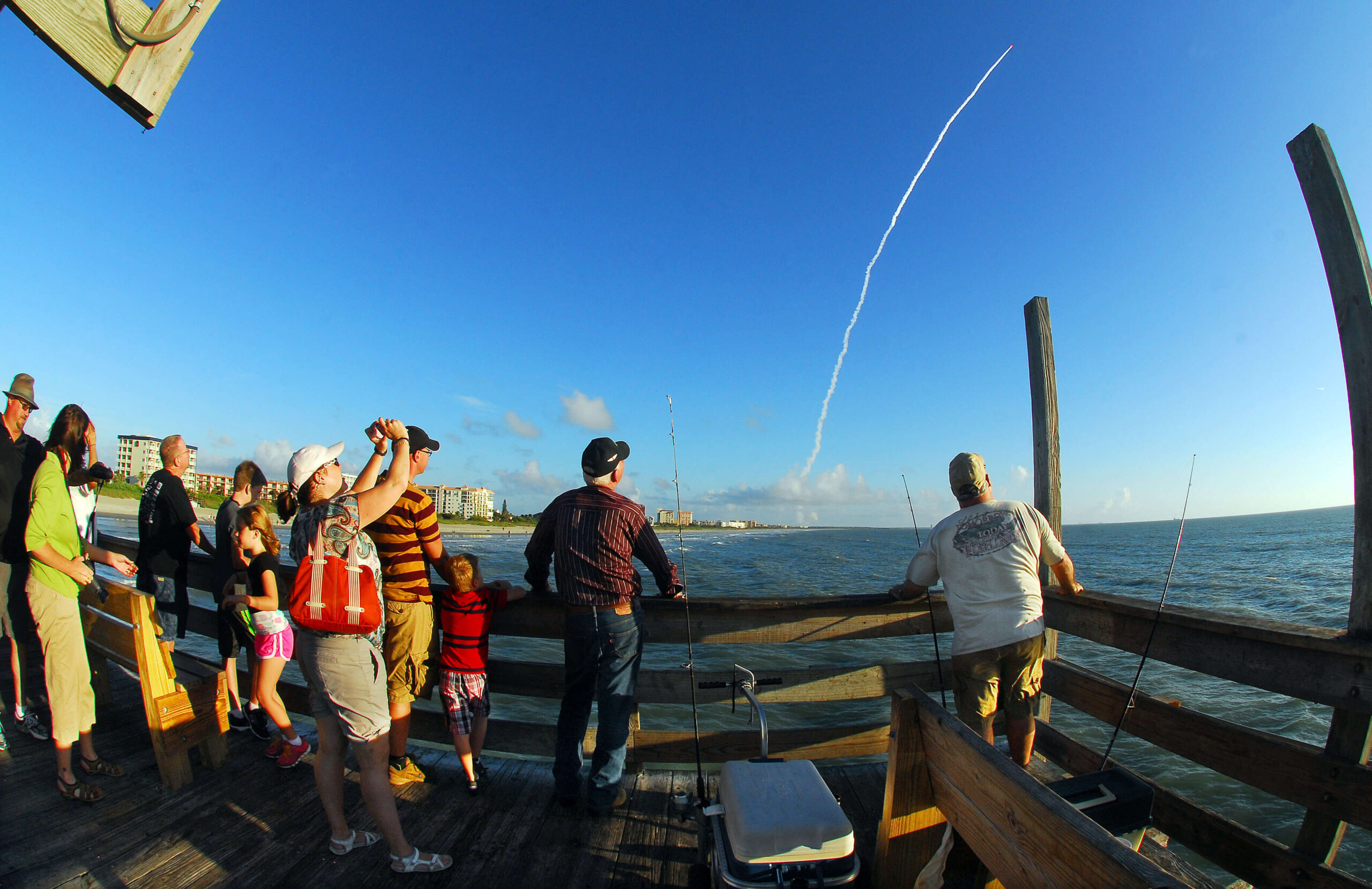 People watch a rocket launch from the pier