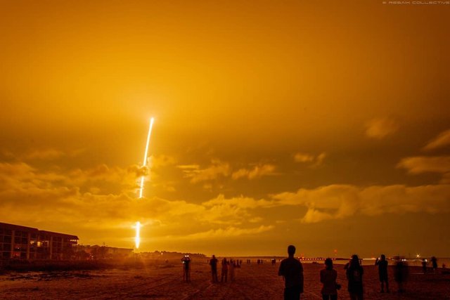 image by @reasix_collective people gather on the beach at night to watch a rocket launch