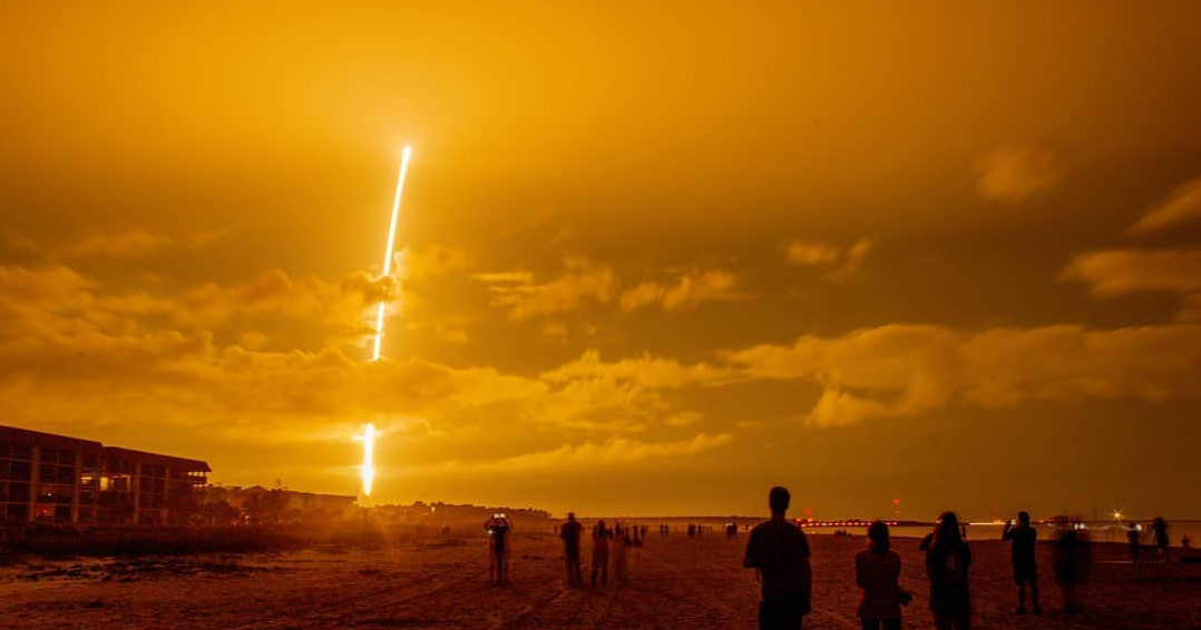 image by @reasix_collective people gather on the beach at night to watch a rocket launch