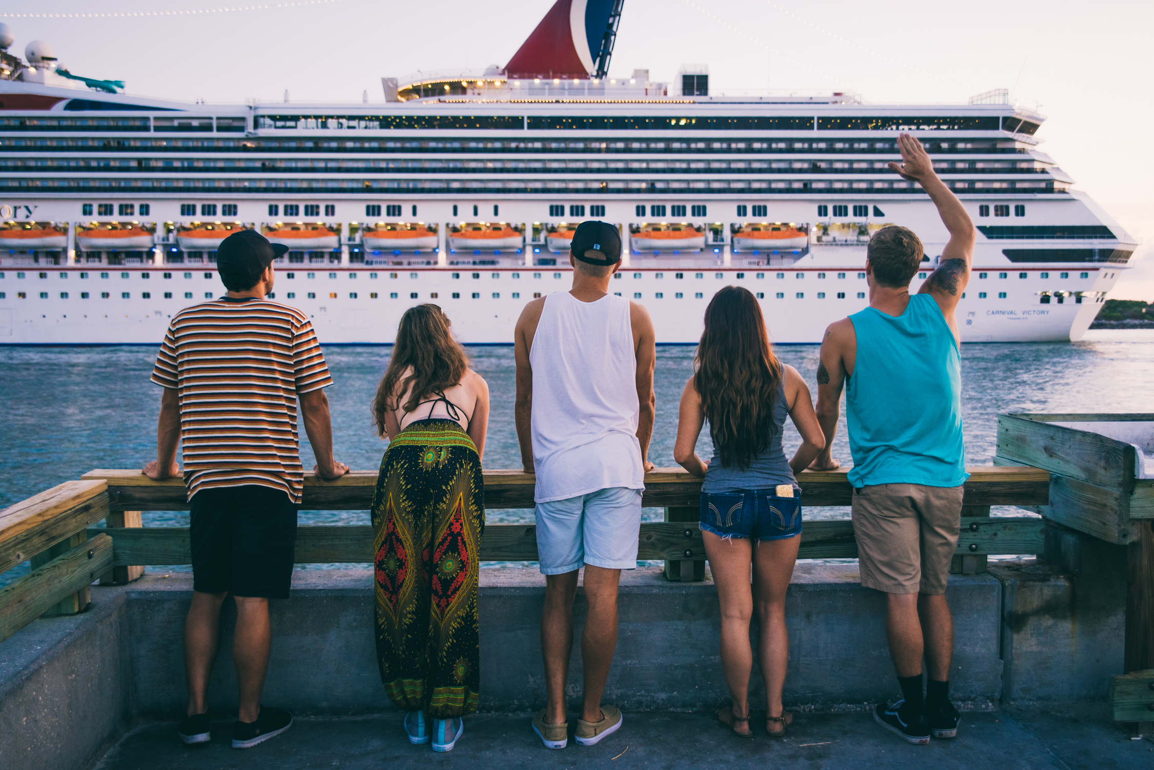 Five individuals watch as a Carnival Cruise ship sails past