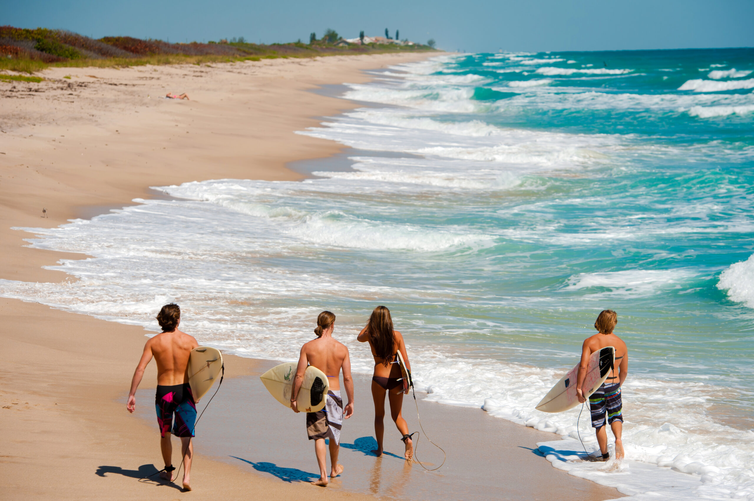 Surfers walking down the beach at Playalinda Beach searching for the perfect wave