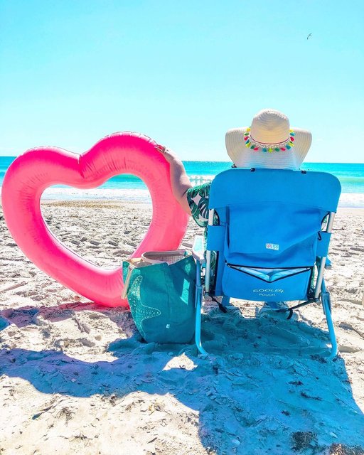 Woman sits at the beach with heart floaty