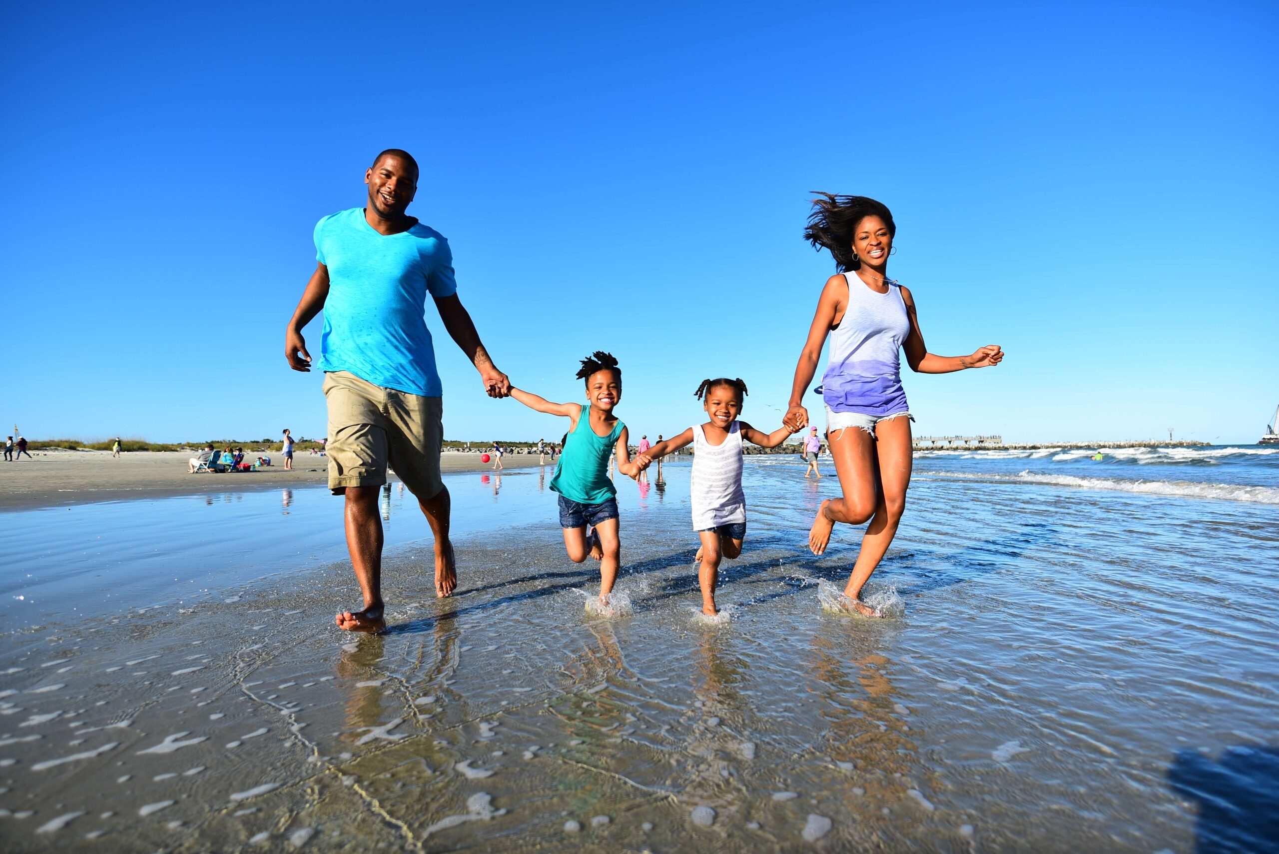 A family with two kids runs in the water on the beach at Jetty Park in Cape Canaveral