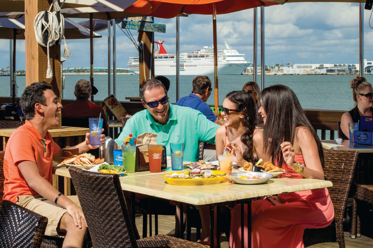 Friends enjoy a meal at Port Canaveral with a Cruise ship in the background
