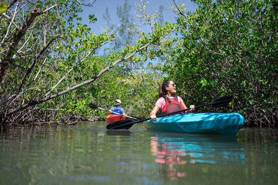 couple paddles on kayaks through the indian river lagoon on Florida's Space Coast